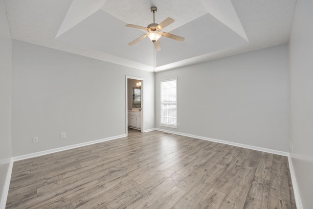 empty room featuring a tray ceiling, light hardwood / wood-style flooring, and ceiling fan