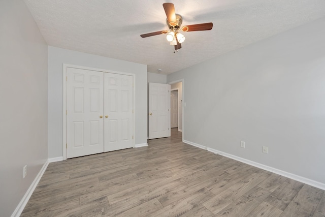 unfurnished bedroom with ceiling fan, light hardwood / wood-style floors, a closet, and a textured ceiling