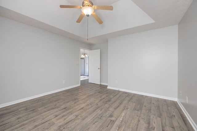 spare room with wood-type flooring and ceiling fan with notable chandelier