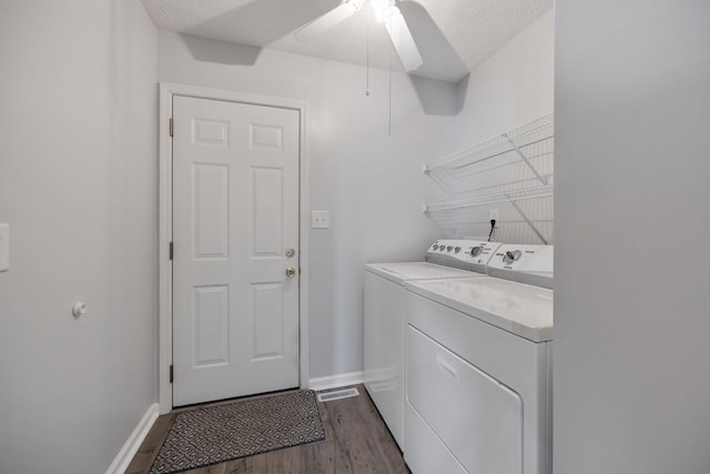 laundry area featuring dark hardwood / wood-style flooring, ceiling fan, washing machine and dryer, and a textured ceiling