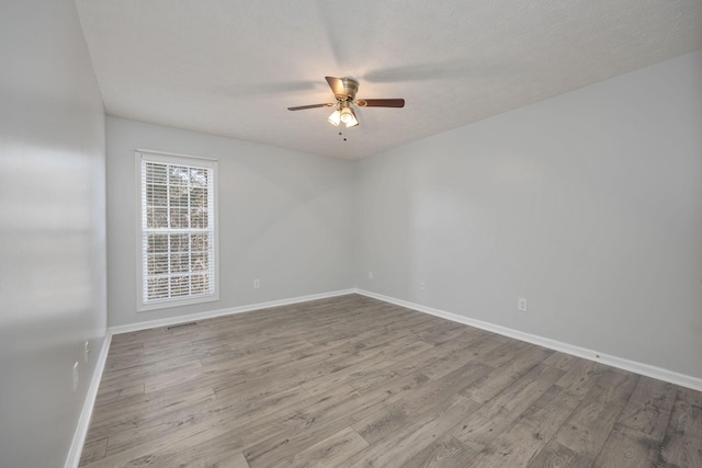 unfurnished room with a textured ceiling, ceiling fan, and light hardwood / wood-style flooring