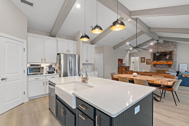 kitchen featuring sink, stainless steel refrigerator, white cabinetry, hanging light fixtures, and tasteful backsplash