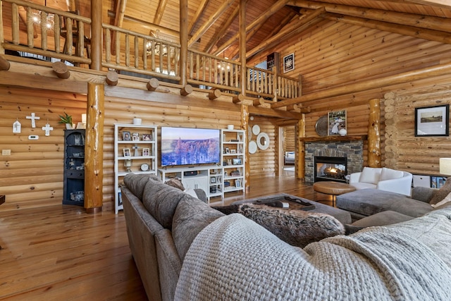 living room with a stone fireplace, high vaulted ceiling, wooden ceiling, beamed ceiling, and log walls