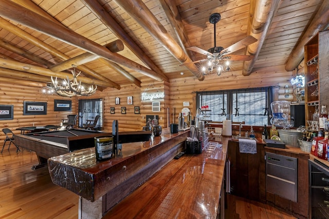 bar with lofted ceiling with beams, wood-type flooring, ceiling fan with notable chandelier, and log walls