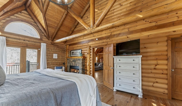 bedroom featuring rustic walls, high vaulted ceiling, a fireplace, access to outside, and light wood-type flooring