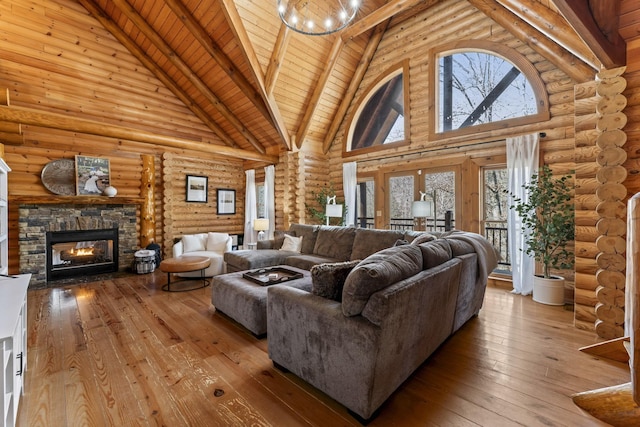 living room with a stone fireplace, log walls, high vaulted ceiling, and light hardwood / wood-style flooring