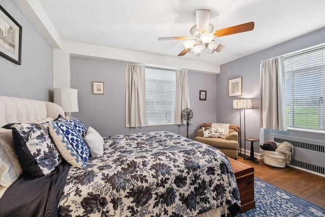 bedroom featuring ceiling fan, radiator heating unit, and wood-type flooring