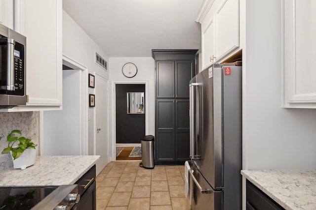 kitchen featuring light stone counters, appliances with stainless steel finishes, and white cabinets