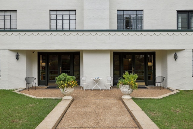 entrance to property with a patio area and a lawn