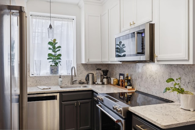 kitchen featuring stainless steel appliances, white cabinetry, light stone countertops, and sink