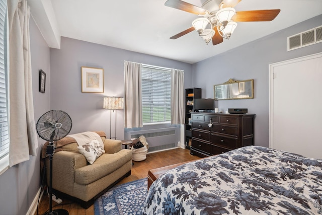 bedroom with ceiling fan, wood-type flooring, and radiator