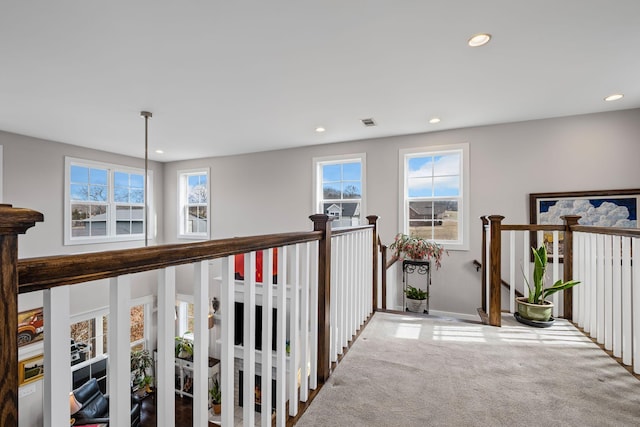 hall with carpet floors and a healthy amount of sunlight