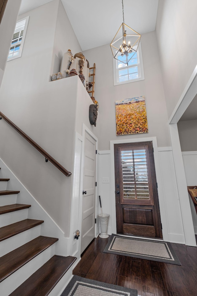 entryway featuring dark wood-type flooring, a towering ceiling, and a notable chandelier