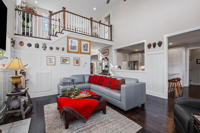 living room with a wealth of natural light, dark wood-type flooring, and a high ceiling