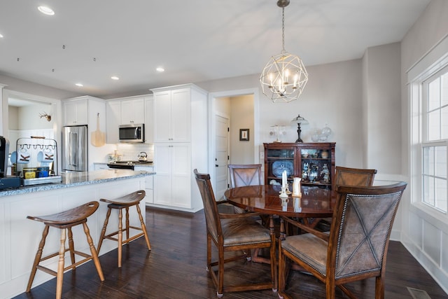 dining area with a notable chandelier, dark wood-type flooring, and a healthy amount of sunlight