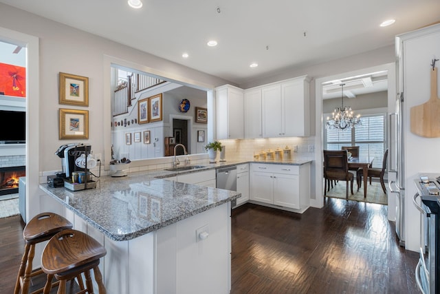 kitchen with sink, hanging light fixtures, a kitchen breakfast bar, kitchen peninsula, and white cabinets