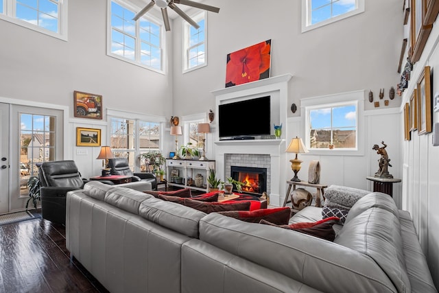 living room with a high ceiling, ceiling fan, dark hardwood / wood-style floors, and a fireplace