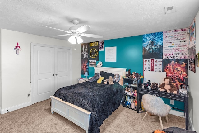 bedroom featuring light carpet, ceiling fan, a closet, and a textured ceiling