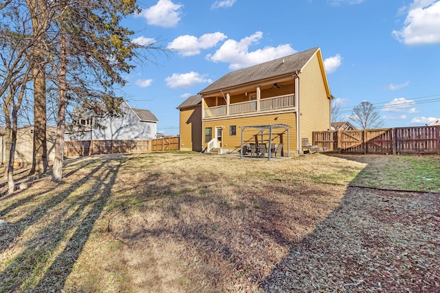 rear view of property with ceiling fan, a lawn, and a balcony