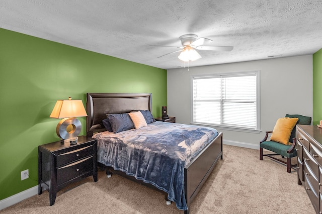 bedroom featuring ceiling fan, light colored carpet, and a textured ceiling