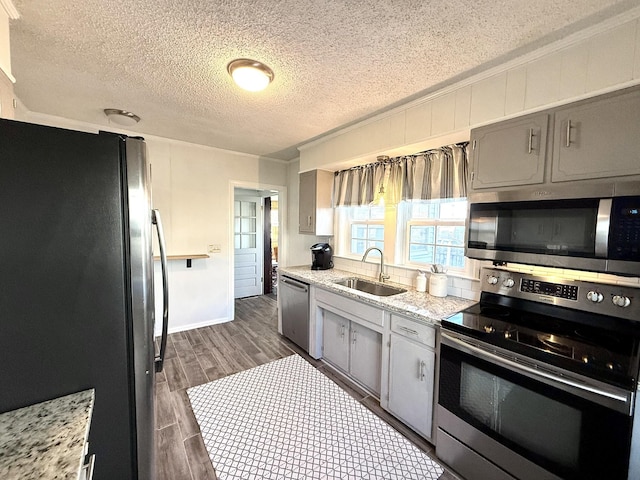 kitchen featuring sink, gray cabinetry, dark hardwood / wood-style flooring, stainless steel appliances, and light stone countertops