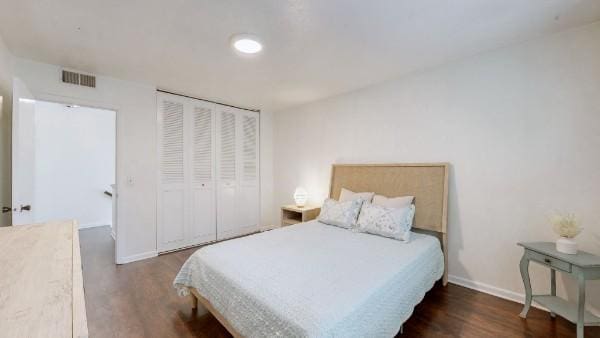 bedroom featuring a closet, wood finished floors, visible vents, and baseboards