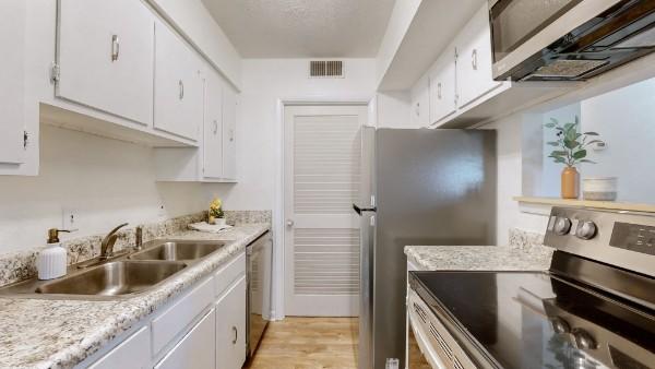 kitchen with white cabinetry, stainless steel appliances, a sink, and light countertops