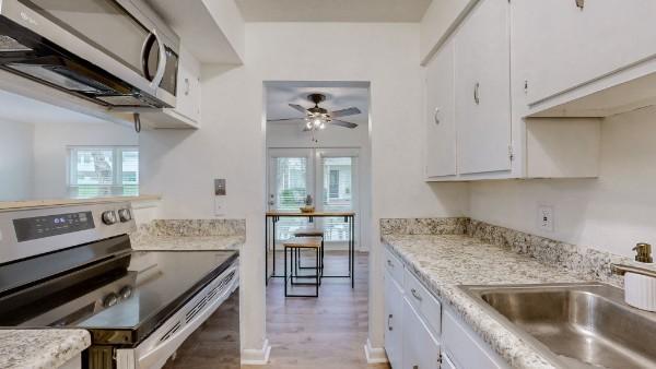 kitchen featuring stainless steel appliances, a sink, a ceiling fan, white cabinetry, and light countertops