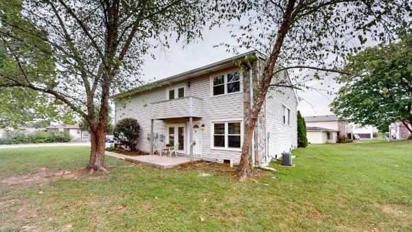 view of front facade with a front yard, a patio, a balcony, and central air condition unit