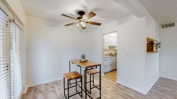 dining area with a ceiling fan, baseboards, visible vents, and light wood finished floors