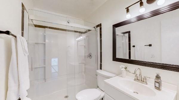 full bathroom with toilet, a stall shower, and vanity