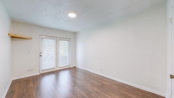 spare room featuring a textured ceiling, baseboards, and wood finished floors