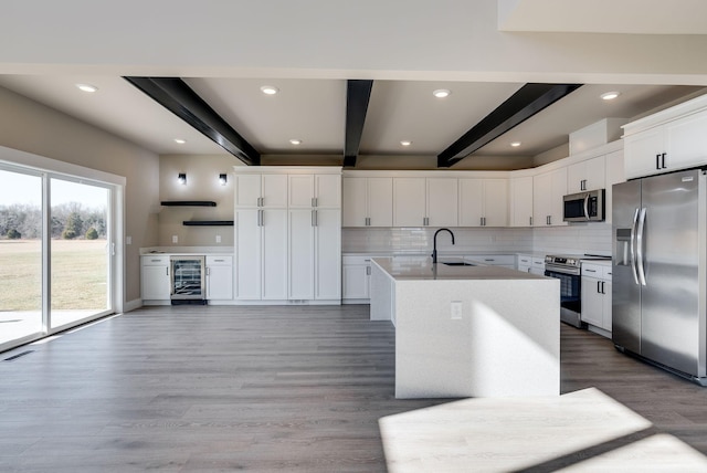 kitchen with sink, beam ceiling, appliances with stainless steel finishes, beverage cooler, and white cabinets