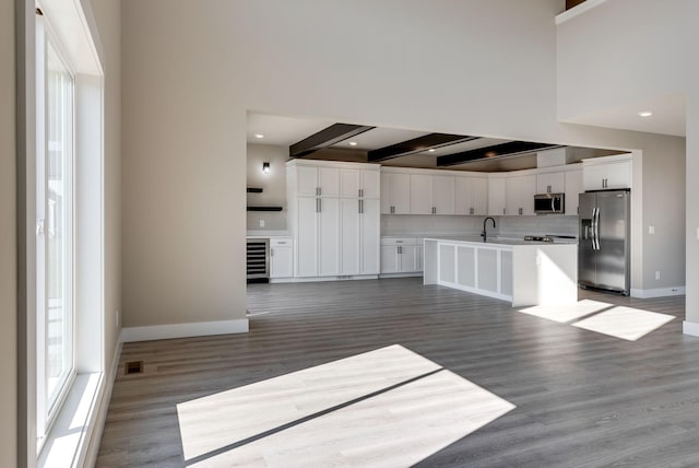 kitchen with sink, hardwood / wood-style flooring, appliances with stainless steel finishes, white cabinetry, and beam ceiling