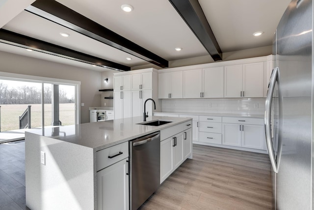 kitchen with stainless steel appliances, beam ceiling, sink, and white cabinets