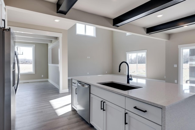 kitchen featuring beamed ceiling, appliances with stainless steel finishes, sink, and white cabinets