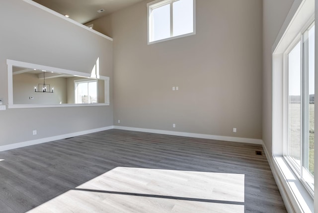 unfurnished living room with a healthy amount of sunlight, dark wood-type flooring, and a chandelier