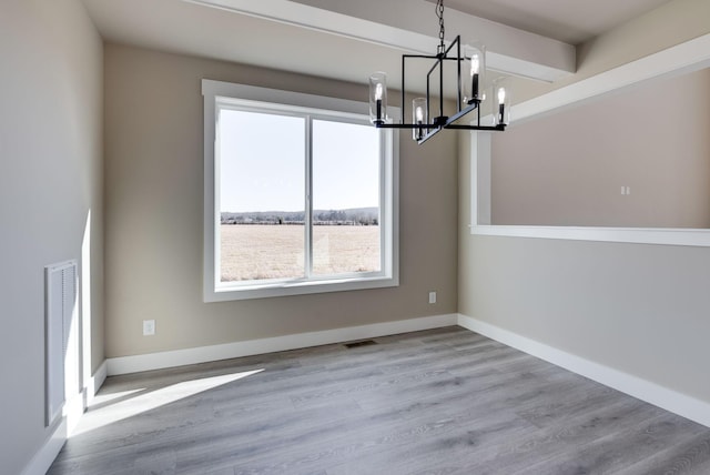 unfurnished dining area with light hardwood / wood-style flooring, a chandelier, and a healthy amount of sunlight