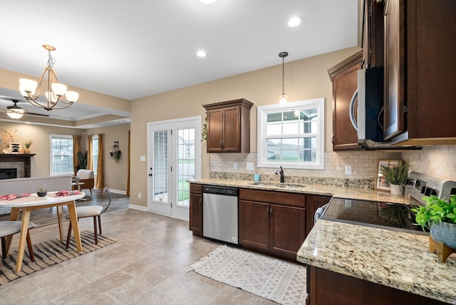 kitchen with hanging light fixtures, a tiled fireplace, appliances with stainless steel finishes, and sink