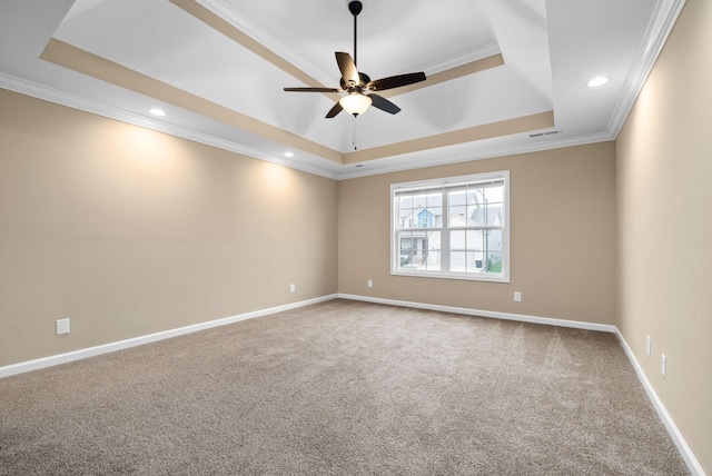 carpeted spare room with ornamental molding, a raised ceiling, and ceiling fan