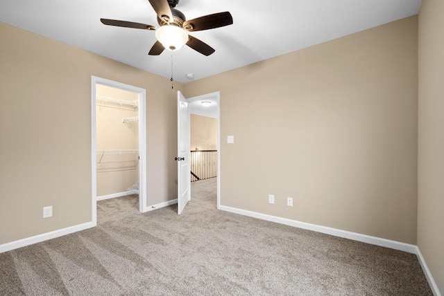 unfurnished bedroom featuring a spacious closet, light carpet, ceiling fan, and a closet