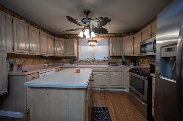 kitchen with appliances with stainless steel finishes, sink, a center island, ceiling fan, and light hardwood / wood-style floors