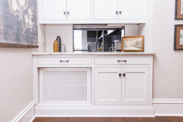 bar featuring dark wood-type flooring and white cabinets