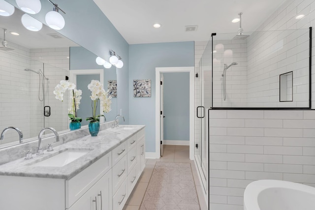 full bathroom featuring double vanity, a stall shower, tile patterned floors, a sink, and a bath