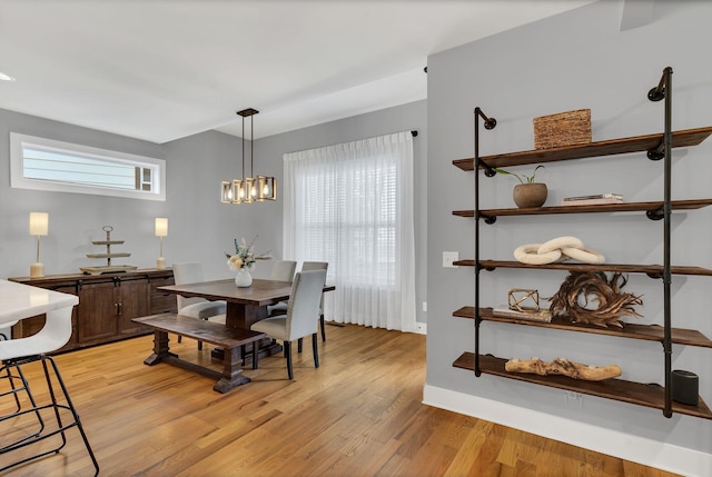 dining space featuring a chandelier, light wood-style flooring, and baseboards