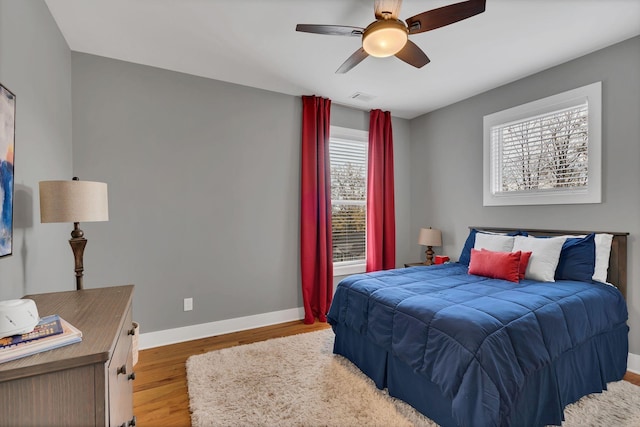 bedroom featuring light wood-style floors, baseboards, visible vents, and ceiling fan