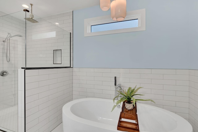 full bath with tile walls, a soaking tub, a wainscoted wall, and a shower stall