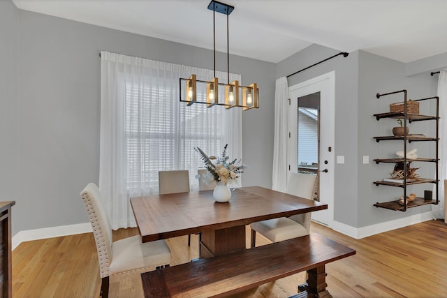 dining room featuring light wood-type flooring, baseboards, and an inviting chandelier