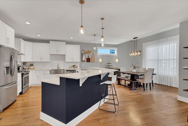 kitchen featuring stainless steel appliances, light wood-type flooring, a sink, and white cabinetry