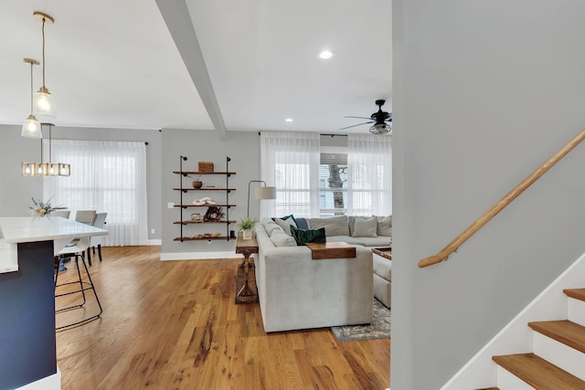 living area with recessed lighting, stairway, light wood-type flooring, beamed ceiling, and baseboards